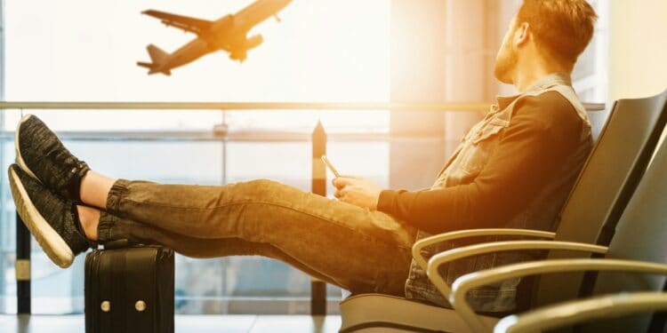 Man Sitting At Airport Watching Plane Flight